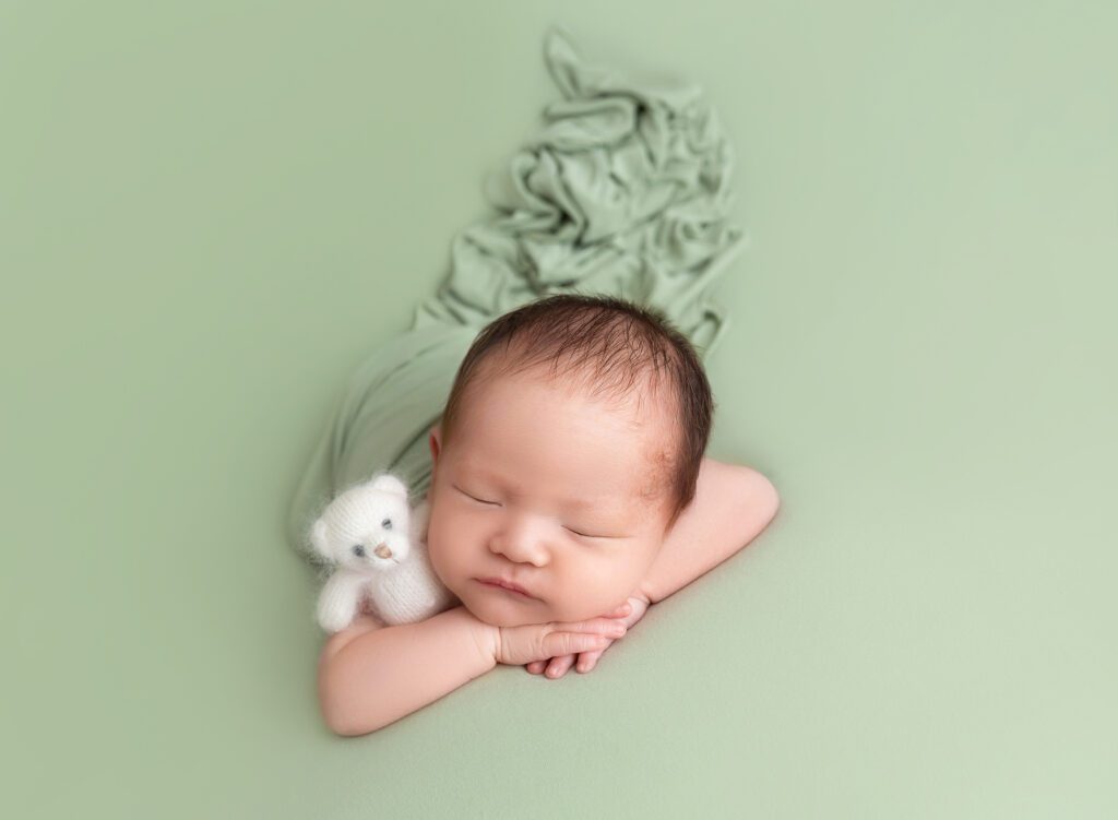 Sleeping Asian American baby wrapped in sage green cloth