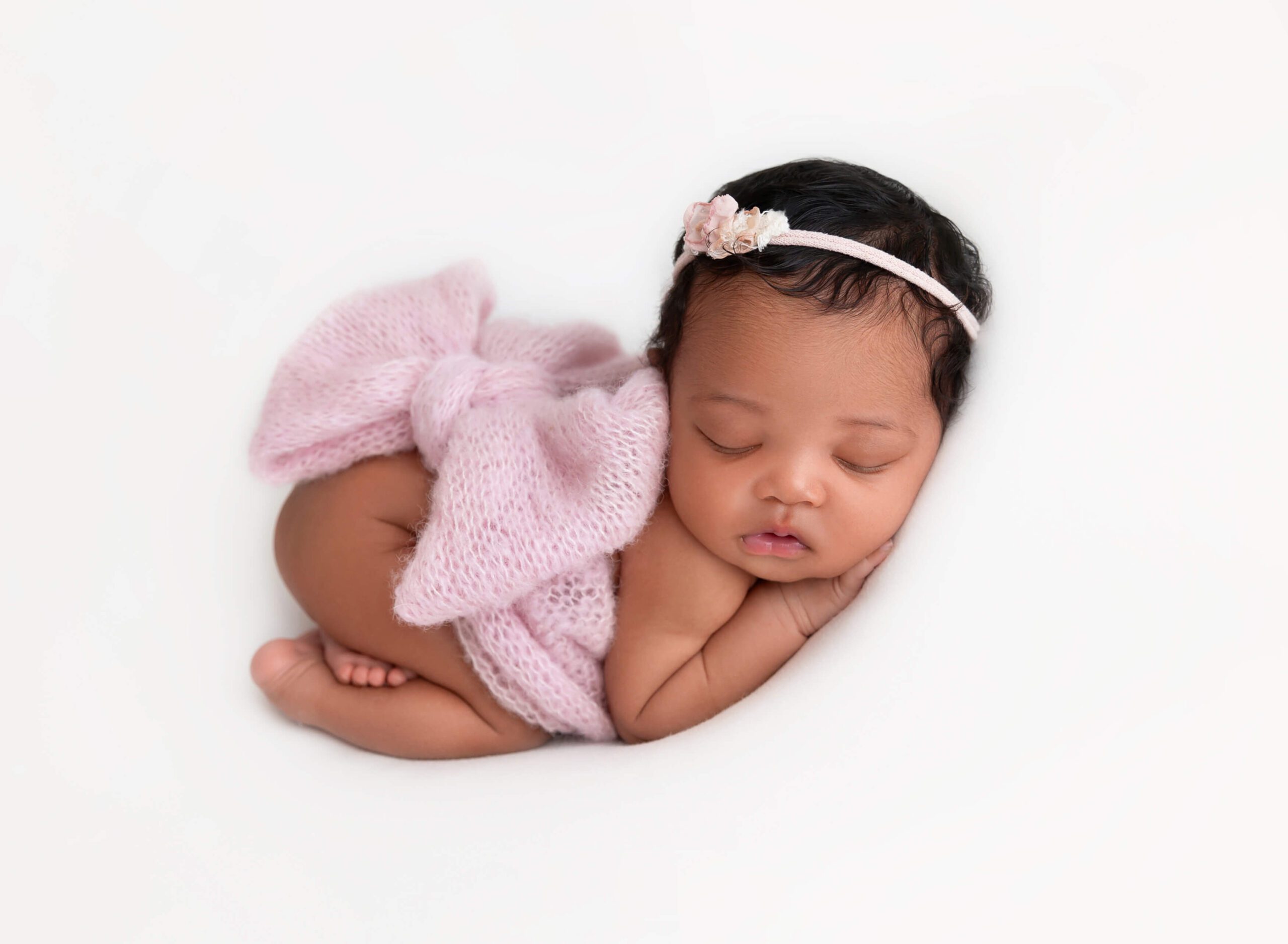 Newborn baby girl wrapped in a pink bow