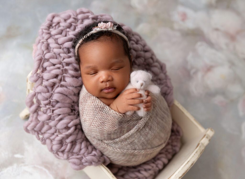 Sleeping infant holding miniature teddy bear in Brooklyn photography studio