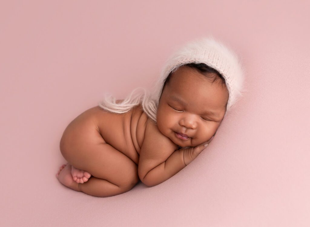 Infant girl asleep on pink beanbag in Brooklyn NY photo studio