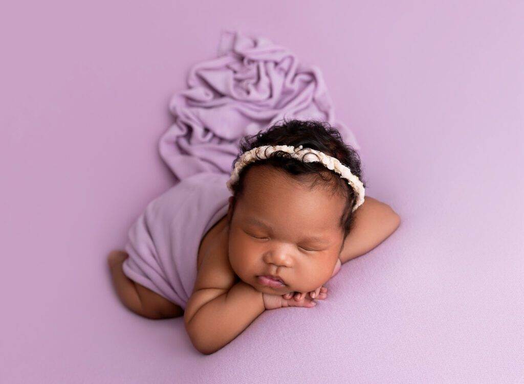 Photograph of a newborn baby girl in Brooklyn NYC wrapped in a soft lavender blanket, peacefully sleeping.