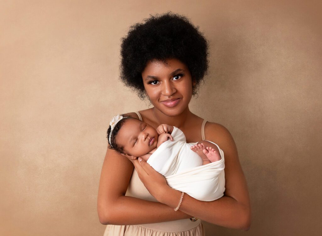 Teen girl holding her new baby sister in her arms during a newborn photoshoot at Rochel Konik Photography in New York