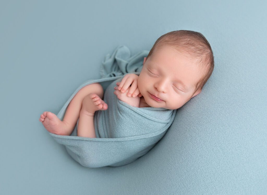 Infant baby boy smiling on teal blanket Brooklyn NYC 