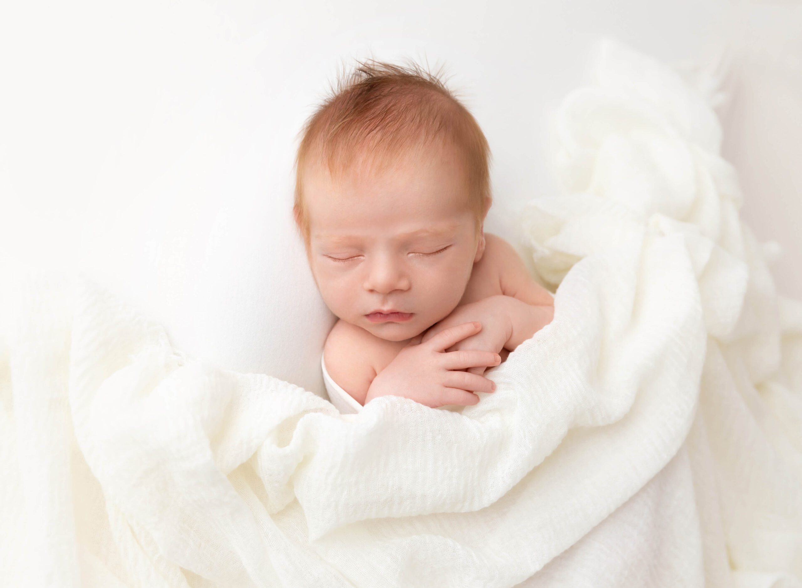 A newborn baby sleeps under a white blanket in a studio after meeting an au pair in new york